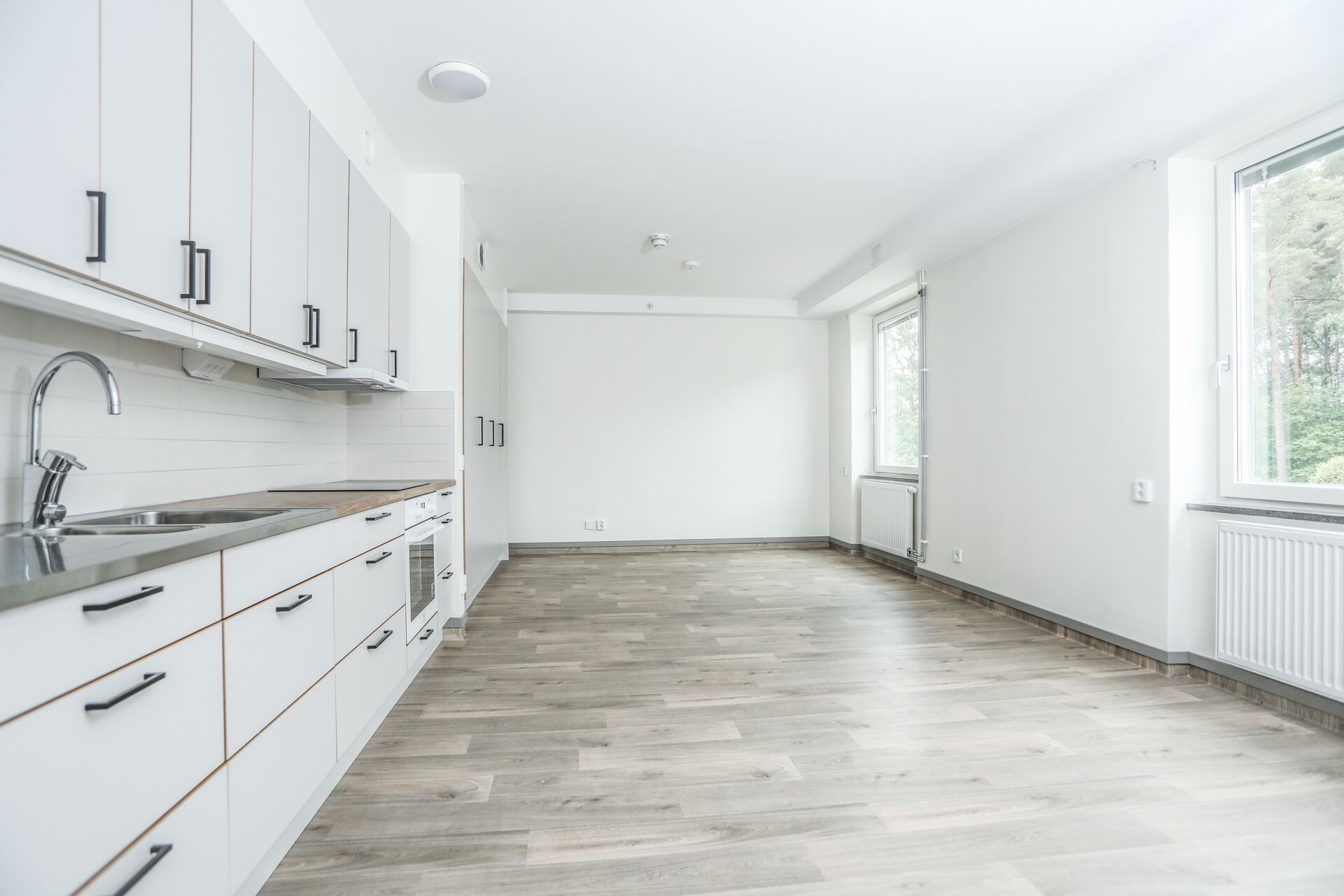 Ljust kök med vita skåp, arbetsytor och fönster mot grönska på Dalviksgatan 71E.