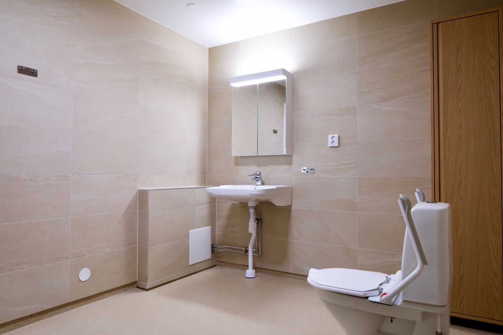 Tillgänglighetsanpassat hygienrum med tvättställ, spegelskåp och stödhandtag på Ljungholmsgatan 12.
