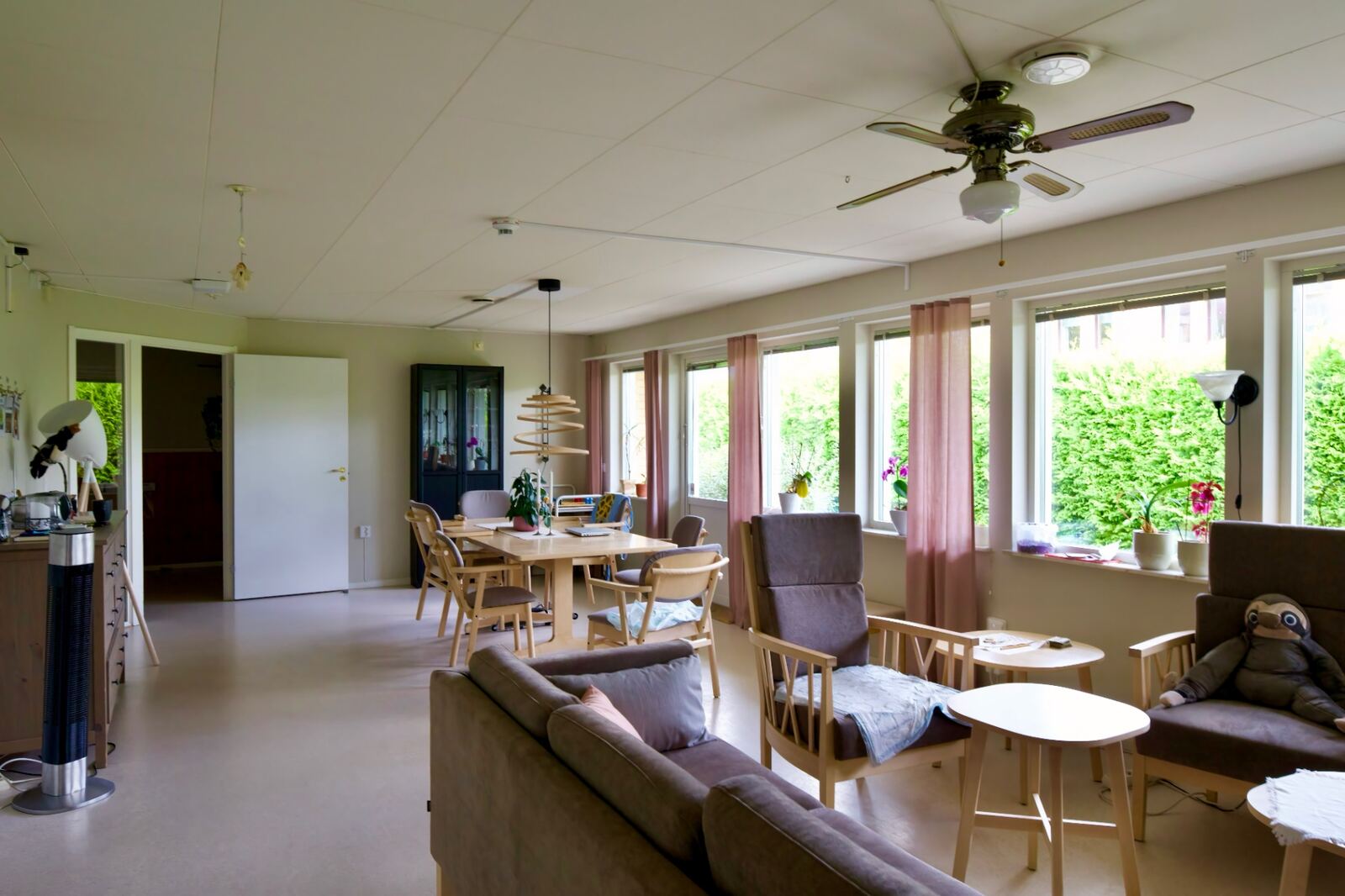 Gemensamhetsyta med matbord, sittgrupp och fönsterrad mot grönska på Ljungholmsgatan 12.